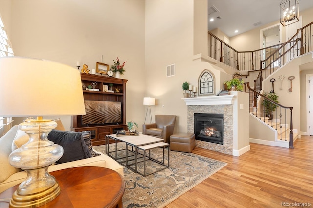 living room featuring light hardwood / wood-style floors, a high ceiling, and an inviting chandelier