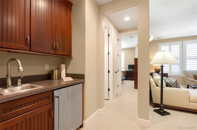 kitchen featuring light carpet, sink, and refrigerator