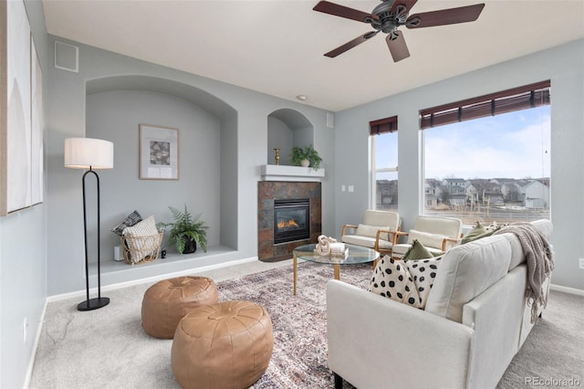 living room featuring visible vents, baseboards, a tile fireplace, ceiling fan, and carpet flooring