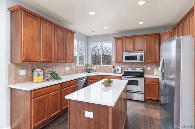 kitchen with stainless steel appliances, dark wood-style flooring, a sink, backsplash, and brown cabinetry