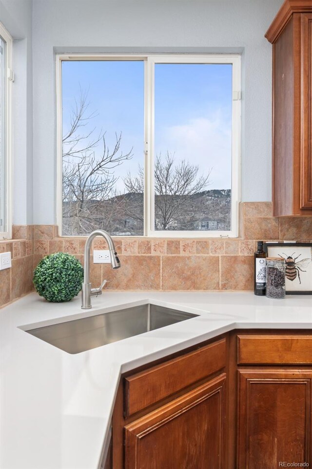 kitchen with brown cabinetry, a sink, and light countertops