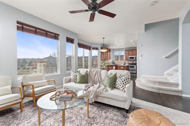 living area with stairs, ceiling fan, wood finished floors, and baseboards