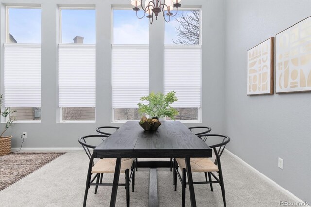 carpeted dining room with baseboards and an inviting chandelier