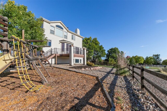 back of property with a chimney, fence, and a playground