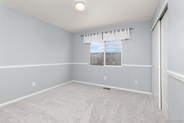 unfurnished bedroom featuring carpet, a closet, visible vents, and baseboards