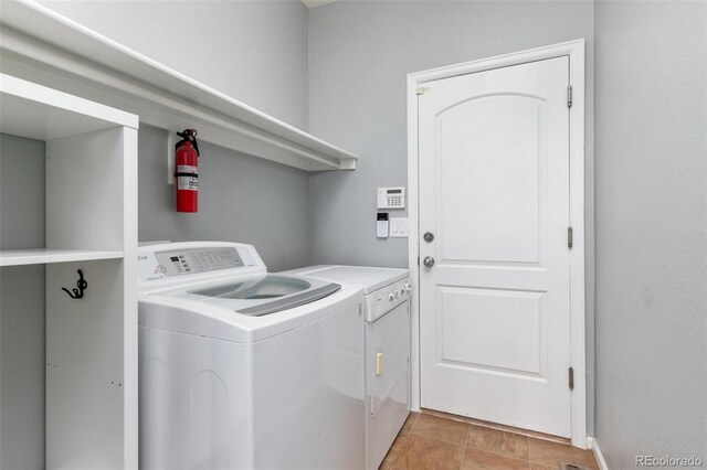 washroom featuring laundry area, washer and clothes dryer, and light tile patterned flooring