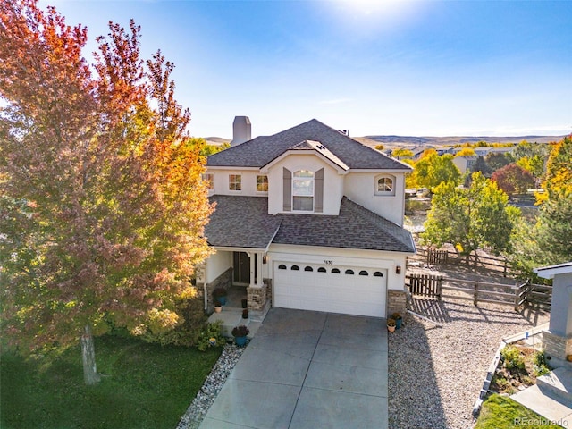 view of front of home with driveway, stone siding, a shingled roof, and fence