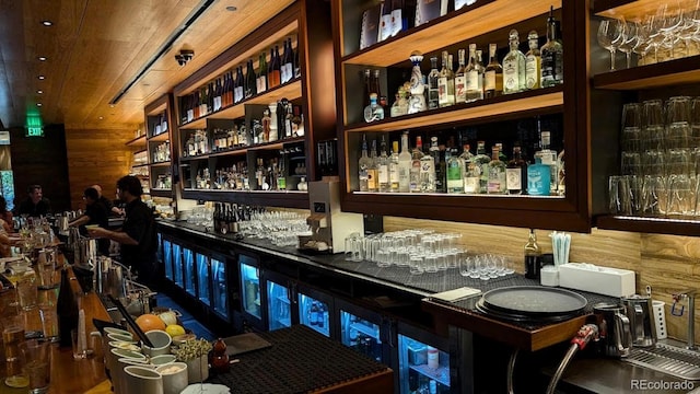 bar featuring a bar, wood walls, and wooden ceiling