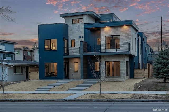 contemporary house with brick siding and a balcony