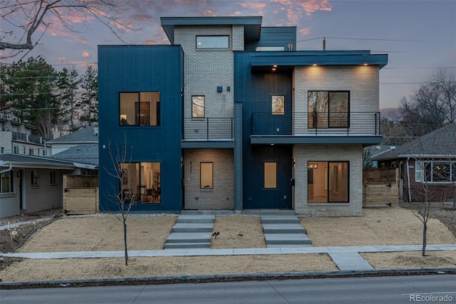 contemporary house with brick siding and a balcony