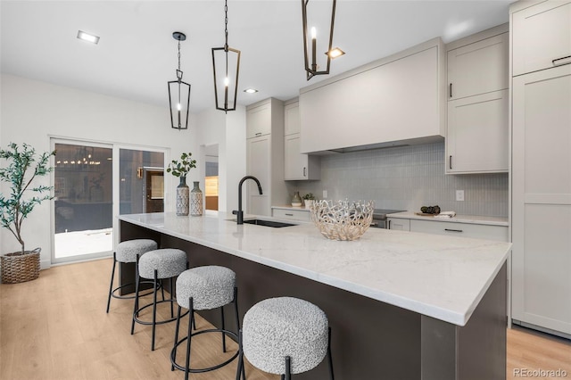 535 Josephine St, Denver, CO 80206 - kitchen with a sink, backsplash, light wood-style flooring, an island with sink, and light stone counters