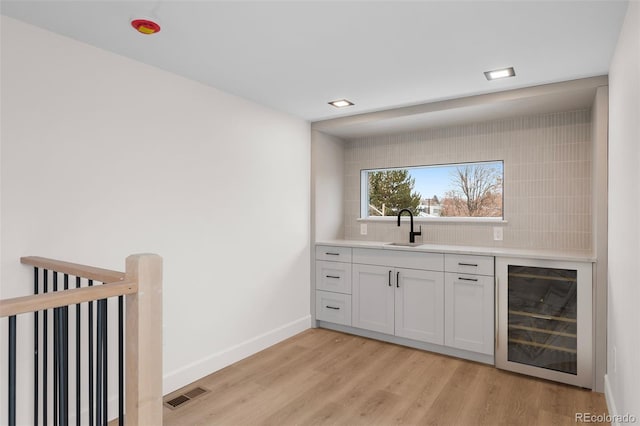 535 Josephine St, Denver, CO 80206 - bar with wine cooler, light wood-style flooring, tasteful backsplash, baseboards, and a sink