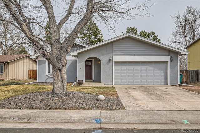 view of front of home with stucco siding, driveway, a garage, and fence