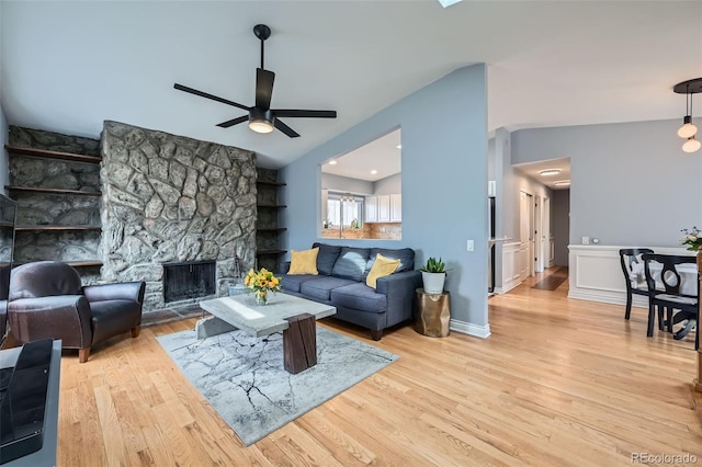 living area featuring a fireplace, lofted ceiling, ceiling fan, and wood finished floors