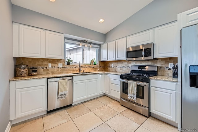 kitchen featuring a sink, tasteful backsplash, white cabinetry, stainless steel appliances, and light tile patterned floors