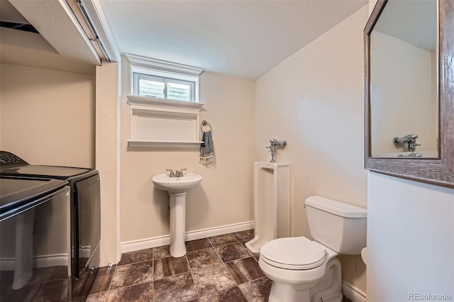 bathroom with washing machine and clothes dryer, toilet, baseboards, and a sink