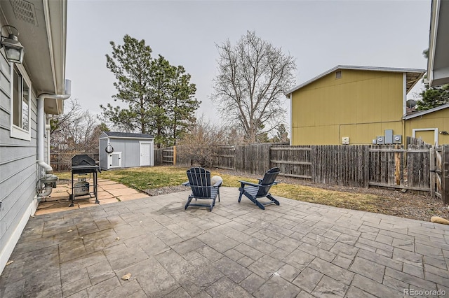 view of patio / terrace featuring an outbuilding, a storage unit, a fenced backyard, and a grill