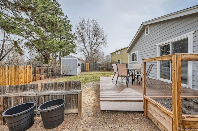 wooden deck featuring an outbuilding, a storage unit, outdoor dining area, and a fenced backyard