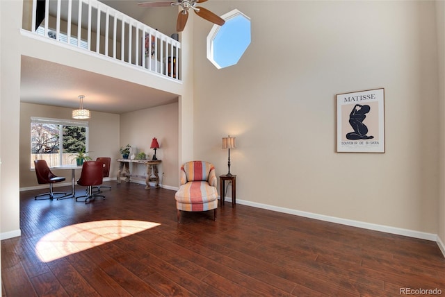 living area featuring ceiling fan, a towering ceiling, and dark hardwood / wood-style floors