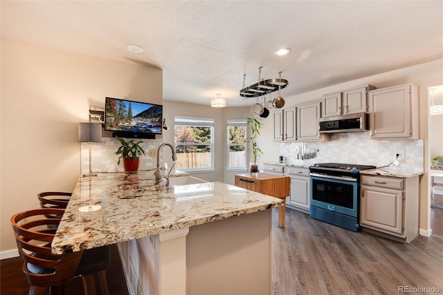 kitchen with sink, a breakfast bar area, decorative backsplash, stainless steel appliances, and light stone countertops