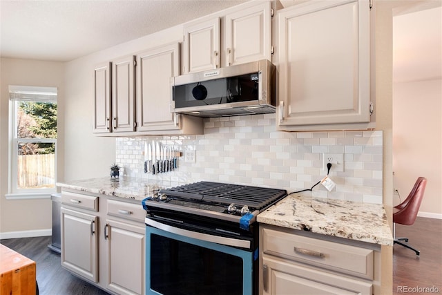 kitchen with stainless steel appliances, tasteful backsplash, light stone countertops, and dark hardwood / wood-style floors