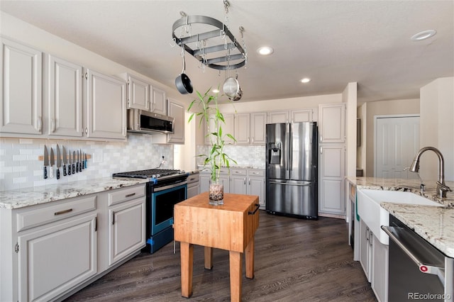 kitchen featuring white cabinetry, stainless steel appliances, dark wood-type flooring, and backsplash