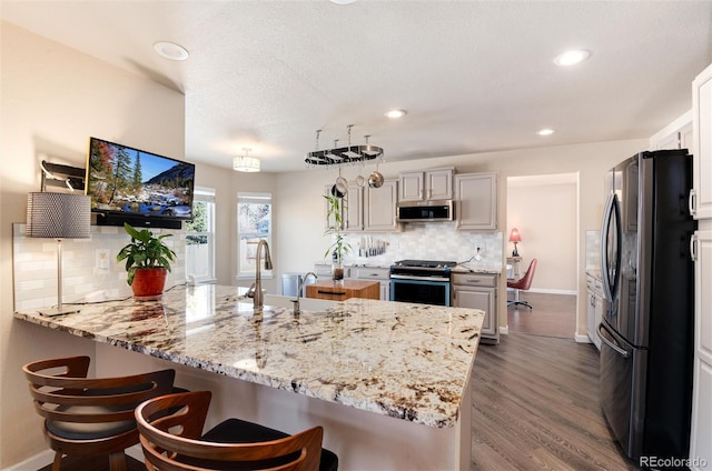 kitchen with pendant lighting, a breakfast bar area, backsplash, stainless steel appliances, and white cabinets