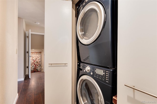 washroom with dark wood-type flooring and stacked washing maching and dryer