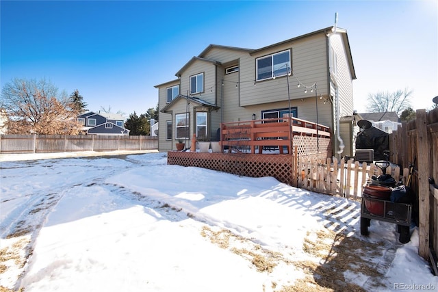 snow covered back of property featuring a deck