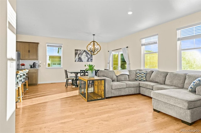 living room with a chandelier, light wood-type flooring, and a wealth of natural light