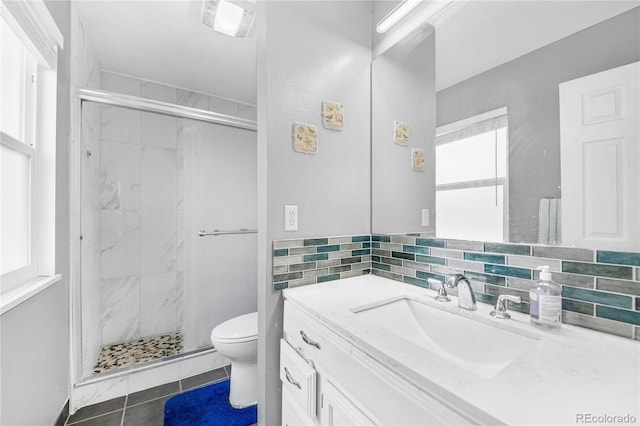 bathroom featuring toilet, vanity, tile patterned floors, and a shower with door