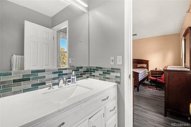 bathroom with vanity, hardwood / wood-style flooring, and decorative backsplash