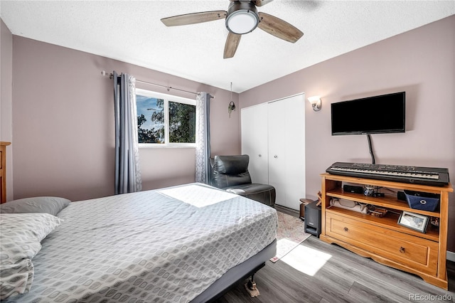 bedroom with a textured ceiling, light wood-type flooring, a closet, and ceiling fan