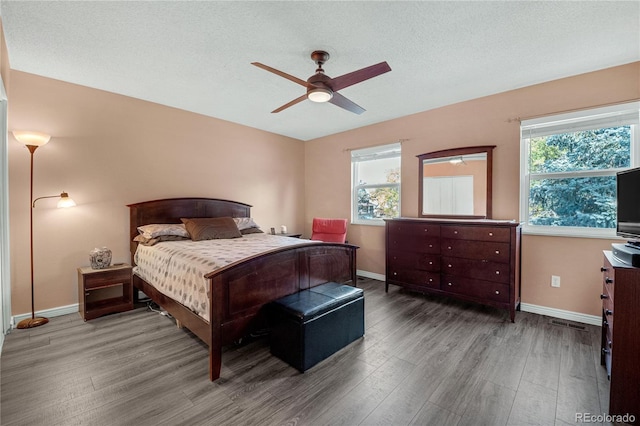 bedroom featuring multiple windows, a textured ceiling, hardwood / wood-style flooring, and ceiling fan