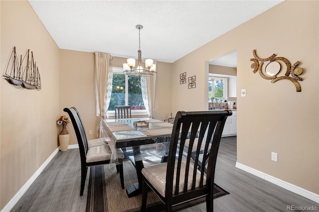 dining space with a textured ceiling, dark hardwood / wood-style floors, and an inviting chandelier