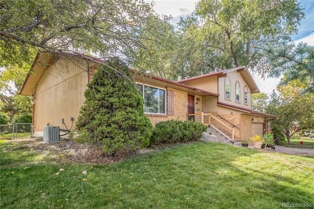 tri-level home with a front yard and cooling unit