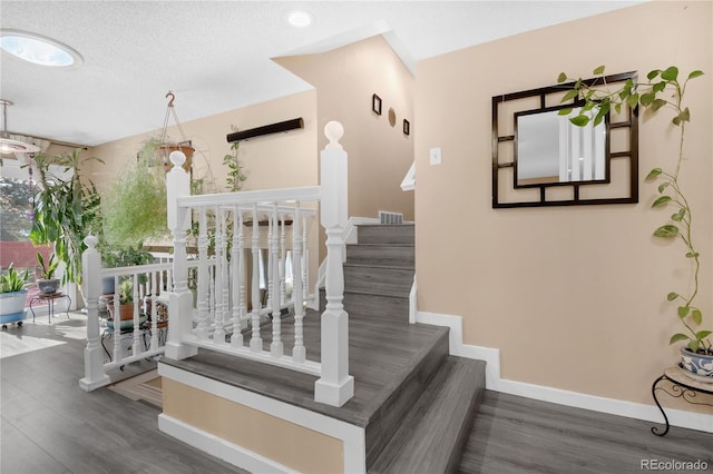 stairs featuring a textured ceiling and hardwood / wood-style floors