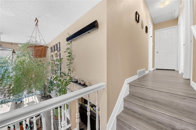 stairway featuring a textured ceiling and hardwood / wood-style floors