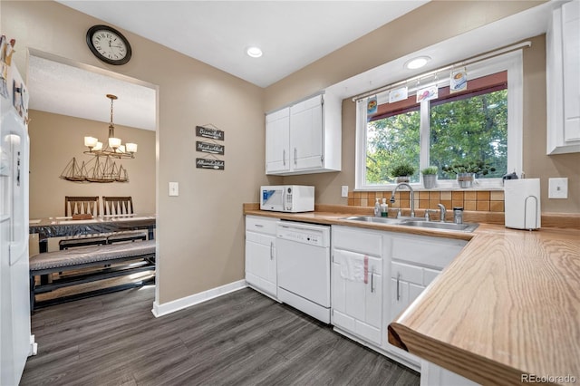 kitchen featuring white appliances, sink, dark hardwood / wood-style flooring, white cabinetry, and pendant lighting