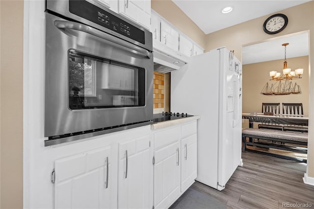 kitchen with white cabinets, stainless steel oven, a chandelier, wood-type flooring, and pendant lighting