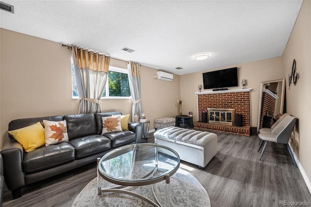 living room featuring a wall unit AC, dark hardwood / wood-style floors, a textured ceiling, and a fireplace