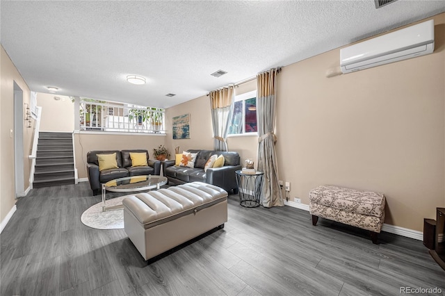 living room with a wall unit AC, a healthy amount of sunlight, a textured ceiling, and dark hardwood / wood-style floors