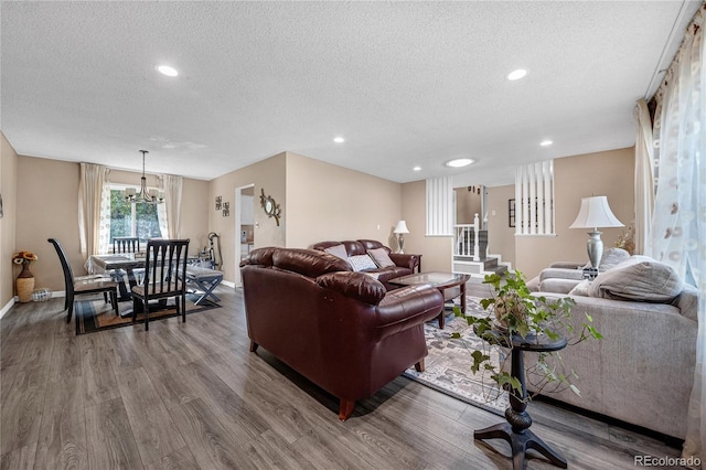 living room with a textured ceiling, a notable chandelier, and hardwood / wood-style flooring