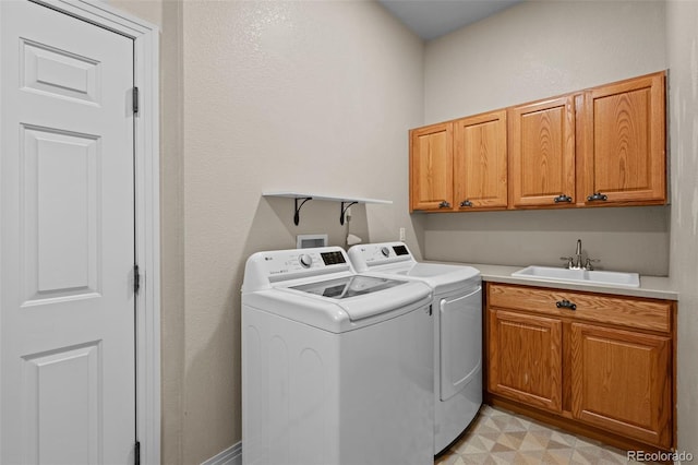 clothes washing area with sink, cabinets, light tile patterned floors, and independent washer and dryer