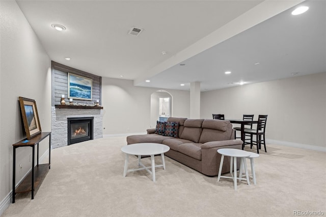 carpeted living room featuring a stone fireplace