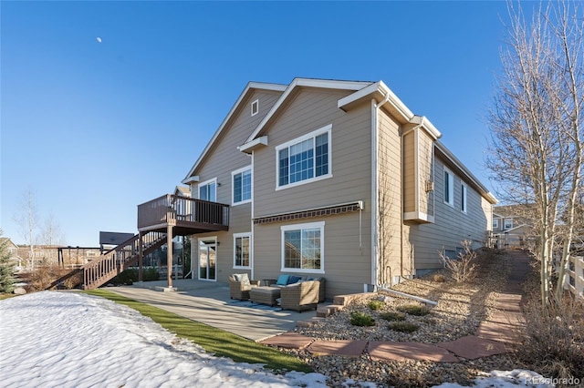 snow covered property featuring a wooden deck, an outdoor hangout area, and a patio area