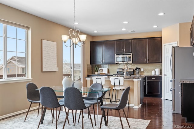 dining room with a healthy amount of sunlight, a chandelier, and dark hardwood / wood-style flooring