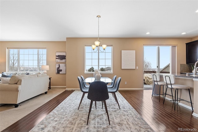 dining area with sink, dark hardwood / wood-style floors, a wealth of natural light, and an inviting chandelier