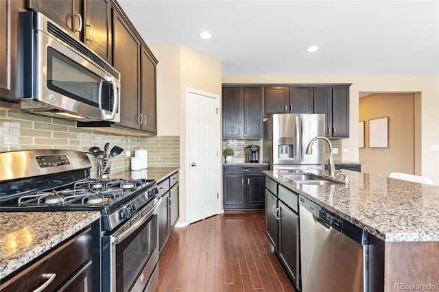 kitchen featuring stainless steel appliances, dark brown cabinets, sink, and a kitchen island with sink