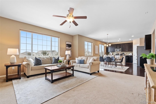 living room with ceiling fan with notable chandelier and light carpet